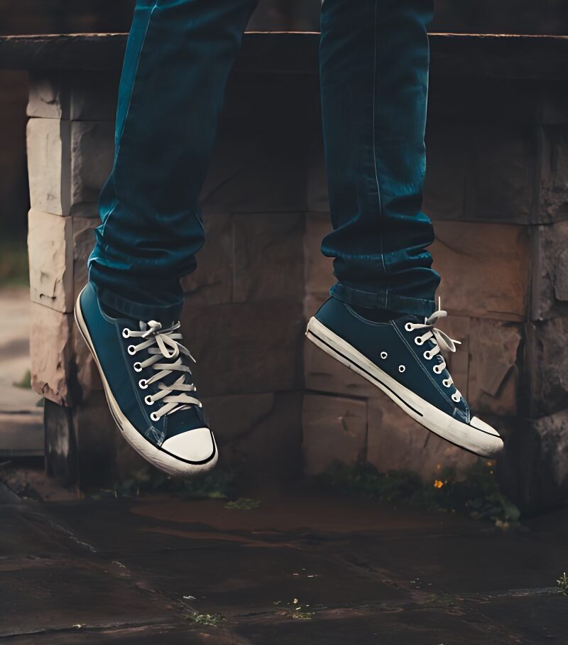 person wearing pair of black low-top sneakers while jumping